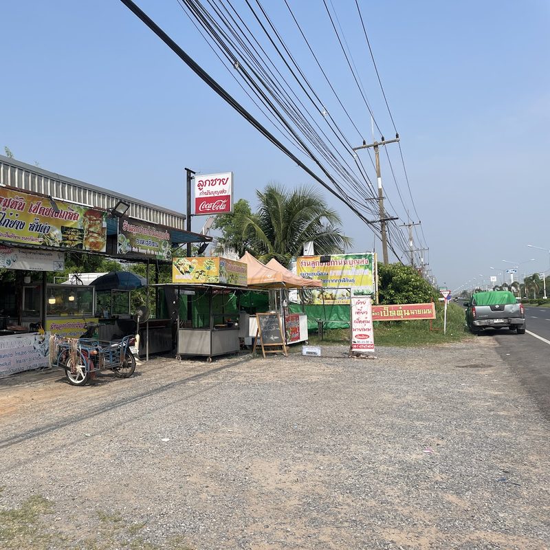 หน้าร้านจากลานจอดรถริมถนนเลี่ยงเมือง ป้ายชื่อร้านและซุ้มเตาย่าง